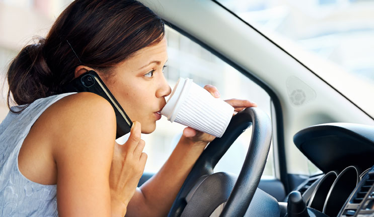 Distracted Driving Woman with Coffee and Cell Phone